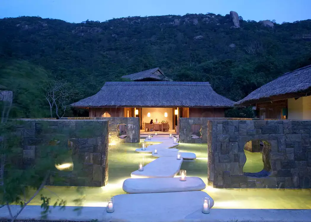 Six Senses Ninh Van Bay seen from the water, with villas set against the granite headland